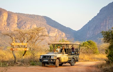 Eine Familie fährt im offenen Jeep durch das Entabeni-Naturreservat – Südafrika Familienreise