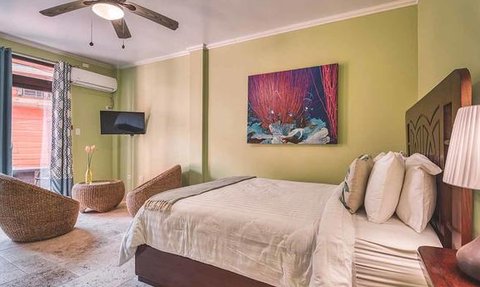 Ein helles Hotelzimmer mit einem großen Bett, einem Fernseher und einer bunten Wandkunst, die Meeresleben darstellt.