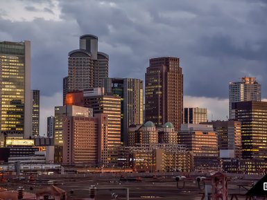 Die Skyline von Osaka bei Dämmerung, mit beleuchteten Wolkenkratzern und dramatischem Himmel im Hintergrund.