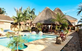 Ein einladender Poolbereich mit Palmen und einem Strohdach, ideal für Entspannung und Erholung unter der Sonne.