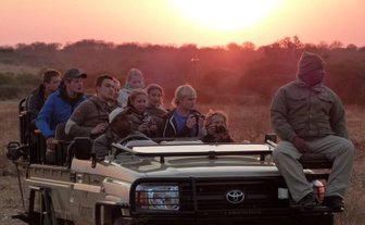 Reisegruppe im offenen Safari-Jeep entdeckt die Tierwelt bei Nacht – Südafrika mit Kindern