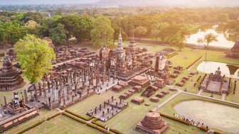 Luftaufnahme des Wat Mahathat Parks in Sukhothai mit Tempelruinen und grüner Umgebung - Thailand mit Kindern