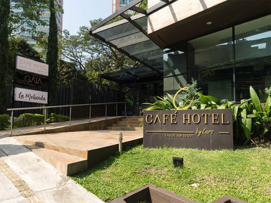 Der Eingangsbereich des Café Hotels in Medellín zeigt eine moderne Architektur mit einer einladenden Treppe und Pflanzen.