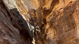 Eine beeindruckende Schlucht mit hohen, steilen Felswänden, in der mehrere Menschen entlang eines schmalen Weges gehen.