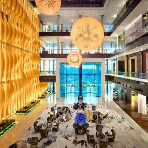 Der elegante Empfangsbereich des Grand Hyatt Abu Dhabi zeigt eine beeindruckende Holzwand und stilvolle Beleuchtung.