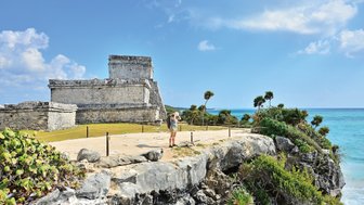 Frau steht auf den Klippen bei Tulum und blickt auf das türkisfarbene Meer – Mexiko Reise mit Kindern