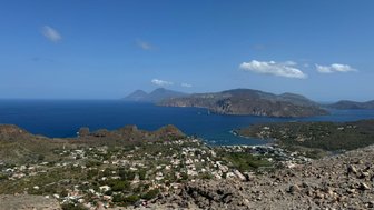 Ein atemberaubender Blick auf die Küste mit sanften Hügeln und dem tiefblauen Meer, das die Landschaft umrahmt.