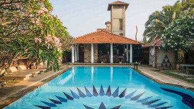 Ein einladender Pool mit blauen Fliesen und einem auffälligen Muster, umgeben von üppigem Grün und blühenden Bäumen.