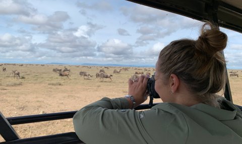 Reisende beobachtet Tiere mit Fernglas während einer Safari – Tansania Familienreise