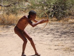 Ein Mann schießt mit einem kleinen Bogen - Namibia mit Kindern