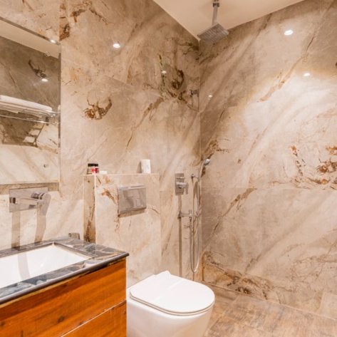 Ein modernes Badezimmer mit eleganten, marmorierten Wänden und einem stilvollen Waschbecken aus Holz und Stein.