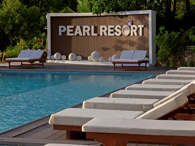 Ein einladender Poolbereich im Pearl Resort, umgeben von Liegen und einer stilvollen Wand mit dem Resort-Namen.