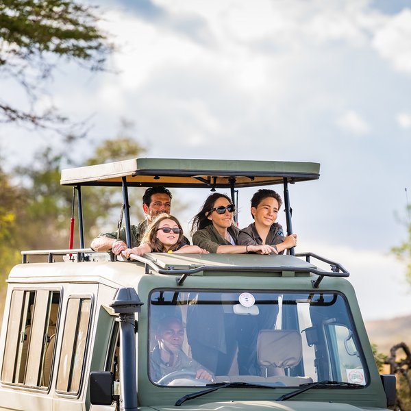 Familiengruppe mit Guide auf Safari im offenen Jeep – Tansania Familienreise