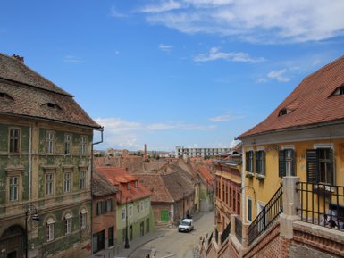Eine malerische Aussicht auf die bunten Häuser von Sibiu, unter einem strahlend blauen Himmel mit wenigen Wolken.