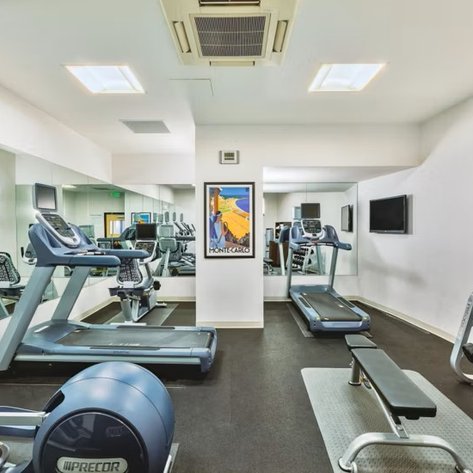 Ein modernes Fitnessstudio mit Laufbändern, Gewichten und Spiegeln an den Wänden, hell erleuchtet und einladend.