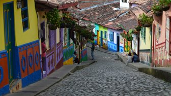 Bunte Häuser säumen die gepflasterte Straße in Guatapé, während Menschen entspannt im Freien sitzen und die Atmosphäre genießen.