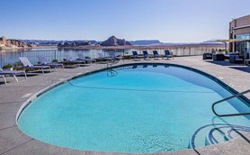 Ein glitzernder Pool mit klarem Wasser, umgeben von Liegen und Blick auf die beeindruckende Landschaft von Lake Powell.