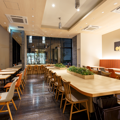 Ein modernes Restaurant mit hellen Holztischen und Stühlen, das eine einladende Atmosphäre für Frühstück bietet.