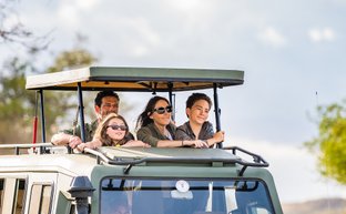 Familie erkundet mit Guide die Tierwelt in einem Safarijeep – Tansania mit Kindern