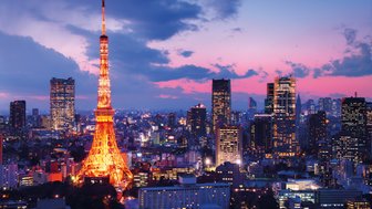 Der Tokyo Tower leuchtet in warmen Farben, während die Stadt unter einem dramatischen Abendhimmel erstrahlt.