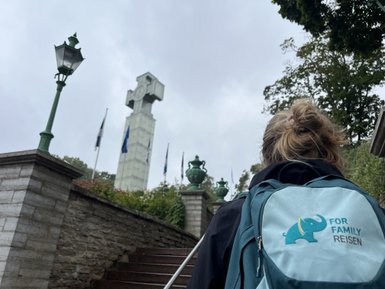 Eine Person mit einem blauen Rucksack geht eine Treppe hinauf, während eine Uhr im Hintergrund sichtbar ist.