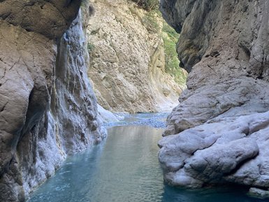 Eine enge Schlucht mit hohen, steilen Felswänden und klarem Wasser, das sanft durch die Mitte fließt.
