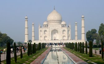 Das majestätische Taj Mahal erhebt sich über einen klaren Wasserkanal, umgeben von gepflegten Gärten und Besuchern.
