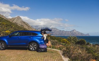 Mutter sitzt im Kofferraum vom Auto und genießt Ausblick – Südafrika Reise mit Kindern