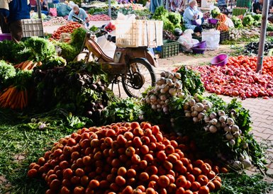 Auf einem Markt in Taroudant sind hohe Stapel frisches Gemüse, darunter Tomaten und Radieschen, zu sehen.