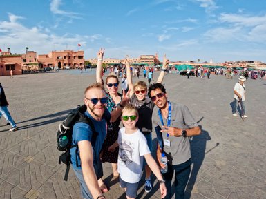 Reiseleiter und Familie posieren gemeinsam für ein Selfie auf Djemaa el Fna Platz in Marrakesch – Marokko Familienreise