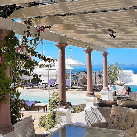 Ein eleganter Lounge-Bereich mit gemütlichen Möbeln, umgeben von bunten Blumen und Blick auf das Meer.