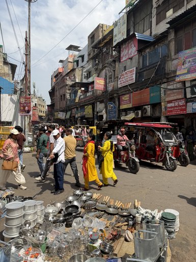 Eine belebte Marktstraße in Alt-Delhi, mit Menschen, die zwischen Ständen und Geschäften umhergehen.