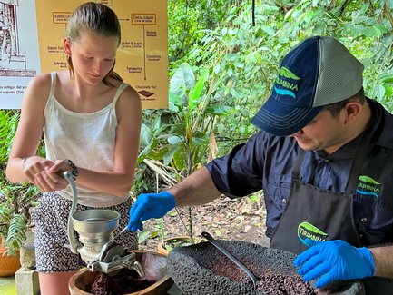 Mädchen und Einheimischer stellen Schokolade bei der Schokoladentour im La Tirimbina Reservat her – Costa Rica mit Kindern