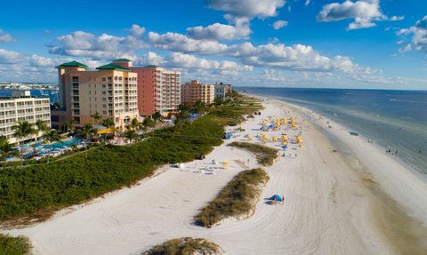 Ein atemberaubender Blick auf den Strand von Fort Myers mit bunten Sonnenschirmen und einem klaren blauen Himmel.