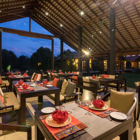 Ein stilvolles Restaurant mit eleganten Tischen, dekoriert mit roten Servietten und einem Blick auf die grüne Umgebung.