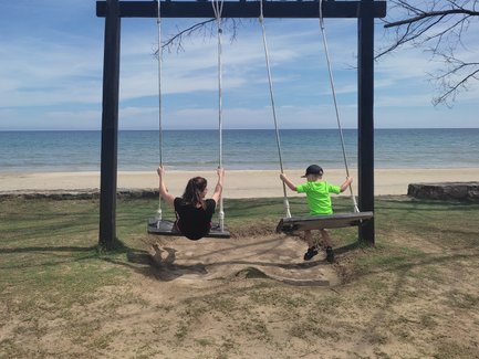 Zwei Kinder schaukeln am Strand des Nexus Resorts – Malaysia & Borneo Familienreise