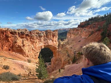 Ein Junge betrachtet die beeindruckende Felsformation im Bryce Canyon, umgeben von roten Klippen und grünen Bäumen.