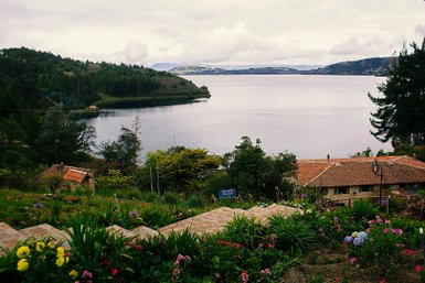Eine malerische Aussicht auf einen ruhigen See, umgeben von üppigem Grün und bunten Blumen in einem Garten.