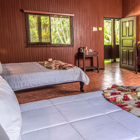 Ein gemütliches Zimmer mit zwei Einzelbetten, umgeben von warmen Holzwänden und einem Fenster mit Blick ins Grüne.