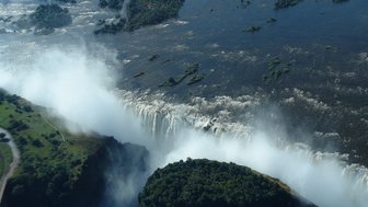 Der majestätische Wasserfall stürzt mit voller Kraft in die Tiefe, umgeben von üppigem Grün und schimmerndem Wasser.