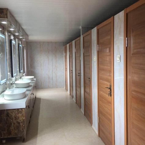 Ein moderner Waschraum mit eleganten, weißen Waschbecken und großen Spiegeln, die sanft beleuchtet sind.