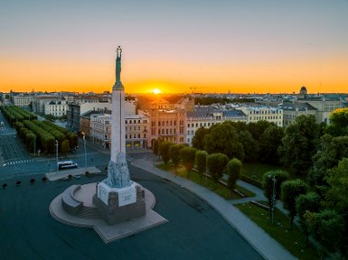 Ein majestätisches Denkmal erhebt sich vor einem atemberaubenden Sonnenuntergang über der Stadt Riga.