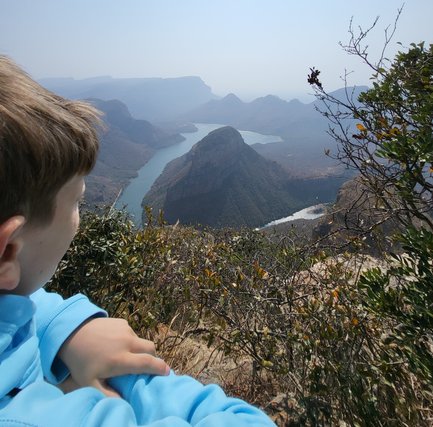 Ein Kind steht am Rand des Blyde River Canyons und blickt fasziniert auf die Landschaft – Südafrika mit Kindern