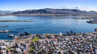 Ein atemberaubender Blick auf Reykjavik, mit bunten Häusern und dem ruhigen Wasser des Hafens im Vordergrund.