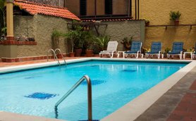 Ein einladender Pool mit klarem Wasser, umgeben von Liegen und üppigen Pflanzen in einem ruhigen Hotelgarten.