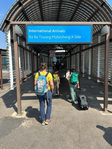 Eine Familie mit Rucksäcken und einem Koffer betritt den Ankunftsbereich eines internationalen Flughafens in Maun.