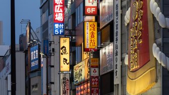 Bunte Neonlichter erhellen die Straßen von Tokio, während Passanten an den Geschäften vorbeigehen und die Atmosphäre genießen.