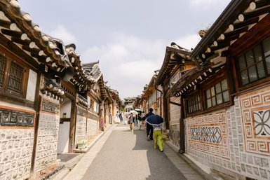 Eine belebte Straße im Bukchon Hanok Village, gesäumt von traditionellen koreanischen Häusern mit charakteristischen Dächern.