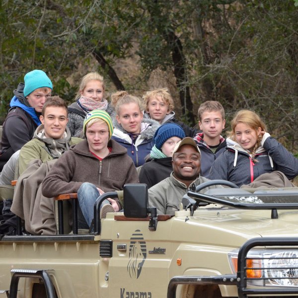 Teenager erleben eine spannende Safari im offenen Jeep durch die südafrikanische Savanne – Südafrika Reise mit Kindern