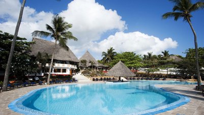 Ein einladender Pool umgeben von Palmen und traditionellen Strohdächern, unter einem strahlend blauen Himmel.